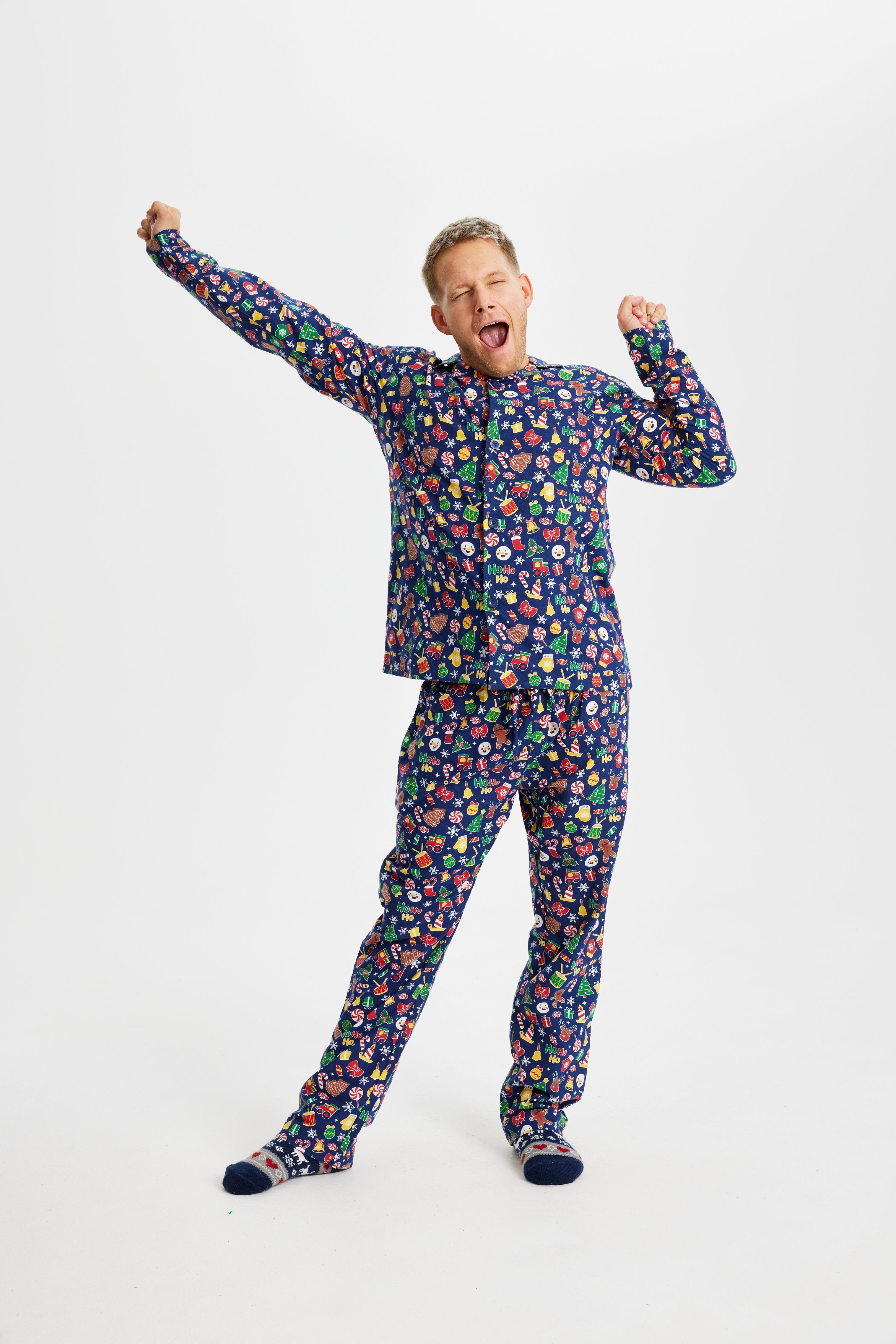 Een geeuwende man in een blauwe kerstpyjama.